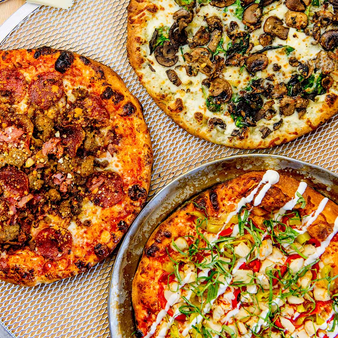 Three thin crust pizzas with different toppings, seen from above
